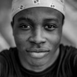 Monochrome portrait of a young man wearing a headscarf, captured in Jos, Nigeria.